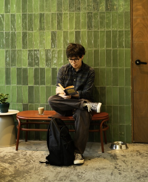 Cliente leyendo junto a la pared de azulejo verde